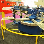 Зона останова 2-х торцевых печатных столов автоматической карусельной печатной машины для нанесения многокрасочных принтов на одежду, футболки, трикотажный крой M&R STRYKER.